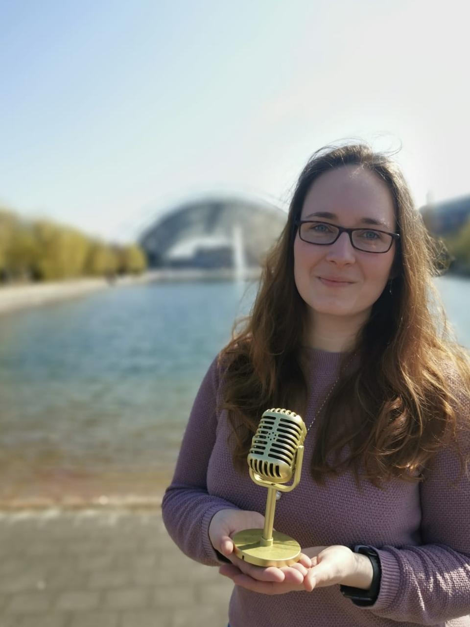 Autorin, die ein goldfarbenes Mikrofon in der Hand hält